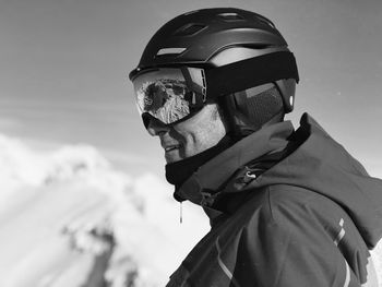 Side view of smiling mature man wearing ski helmet against sky