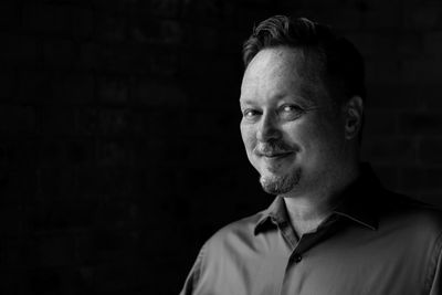 Portrait of smiling mature man standing against black background