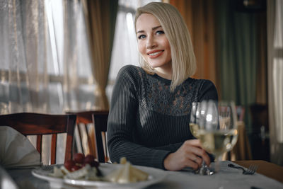 Portrait of a smiling young woman with drink in restaurant