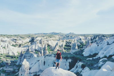 Scenic view of young man standing on a stone against rock formations