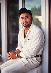 Portrait of young man sitting on window