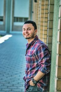 Side view portrait of smiling young man standing by walkway