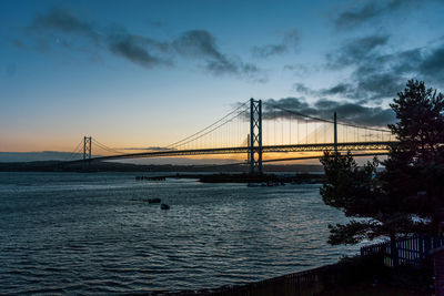 Silhouette bridge over river against sky during sunset