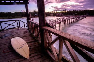 Wooden railing by river against sky