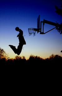 Silhouette of man playing basket