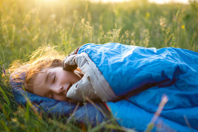 Cute girl in sleeping bag on field