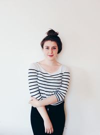 Portrait of young woman standing against white background