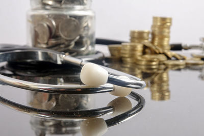 Close-up of stethoscope with coins on table against white background