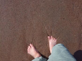 Low section of man standing on sand