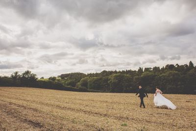 Couple standing on field against sky