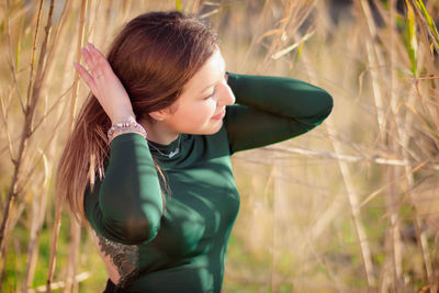 Young woman holding hair on field