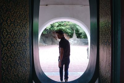 Rear view of man standing by window