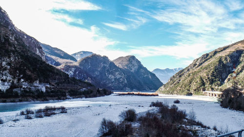 Scenic view of lake by snowcapped mountains against sky