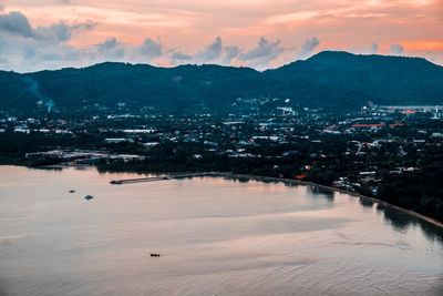 High angle view of townscape by sea against sky during sunset