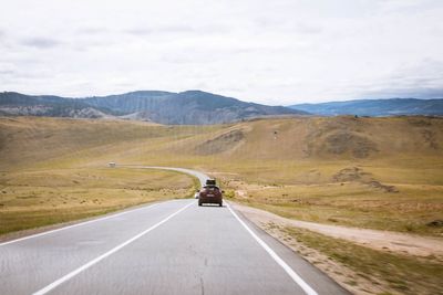 Rear view of man riding motorcycle on road