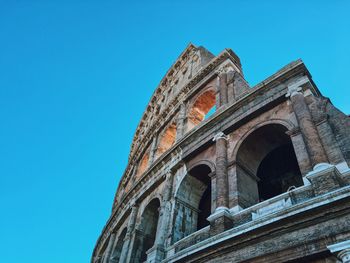 Low angle view of coliseum against clear blue sky