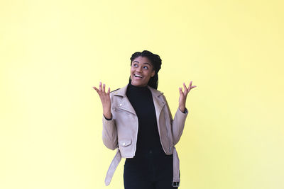 Happy young woman standing against gray background