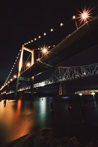 Low angle view of illuminated bridge over river at night