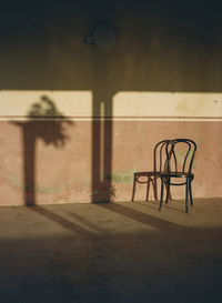 Empty chairs and table against wall