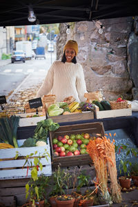 Portrait of happy woman standing by market stall