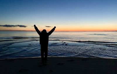 Silhouette of woman standing on beach against clear sky with arms triumphant at chatham, cape cod