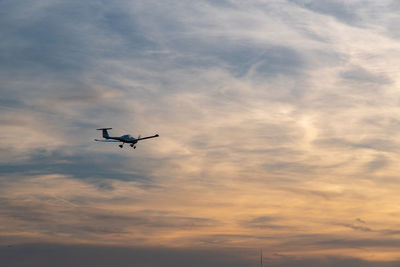 Low angle view of silhouette airplane flying against sky during sunset