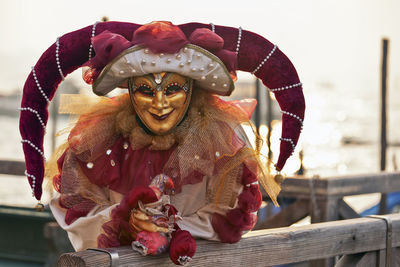Portrait of person wearing venetian mask while leaning on railing