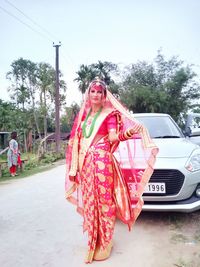 Woman standing by road against sky