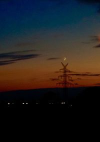 Silhouette of electricity pylon at sunset