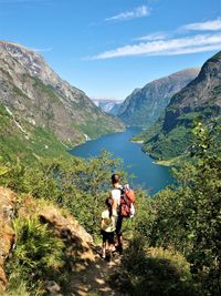 Rear view of father and daughter looking at river while standing on mountain in forest