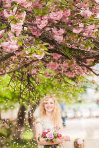 Young woman with pink flowers on tree