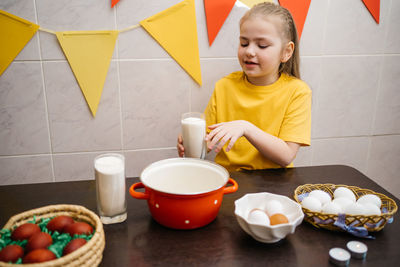 Girl in the kitchen cooks, ingredients and eggs on the table