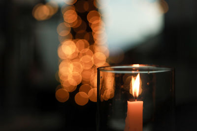 Close-up of illuminated candles on glass