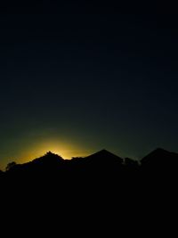 Silhouette mountains against clear sky at night