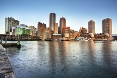 River by buildings in city against clear sky