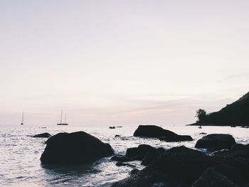 Rocks on beach against sky during sunset