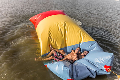 High angle view of happy friends lying on inflatable equipment floating in lake