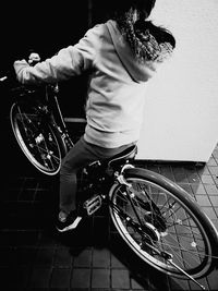 Rear view of woman riding bicycle against wall