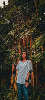 Portrait of young woman standing against plants