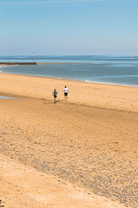 Rear view of men on beach against sky