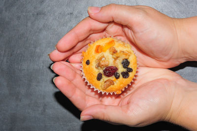 Cropped hands of woman holding cupcake over table