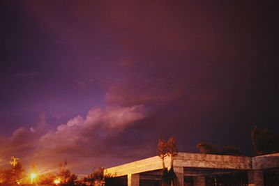 Low angle view of trees against dramatic sky at night