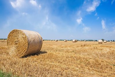 Hay bales on field against sky