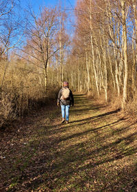 Rear view of woman walking on dirt road in forest