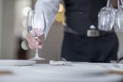 Waiter placing wine glasses on restaurant table