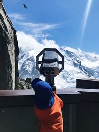 Rear view of man and snowcapped mountains against sky