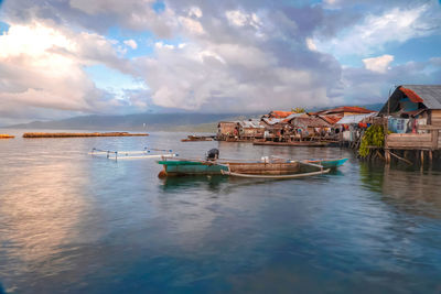 Boats in sea by houses against sky