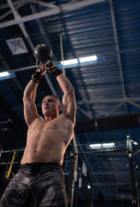 Powerful bodybuilder lifting kettlebell in gym