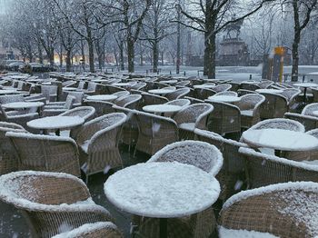 Snow covered chairs and tables on street