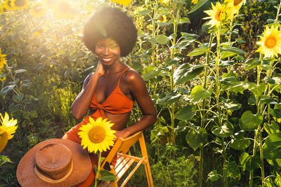 Portrait of smiling woman standing by sunflower